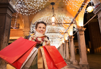 Wall Mural - Happy woman with shopping bags looking into distance in Venice