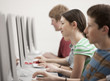 © Mint Images - A group of young people, boys and girls, students in a computer class working at screens.