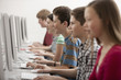 © Mint Images - A group of young people, boys and girls, students in a computer class working at screens.
