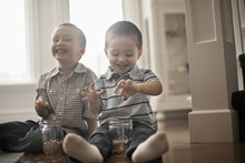 Two Children Playing With Coins, Dropping Them Into Glass Jars.