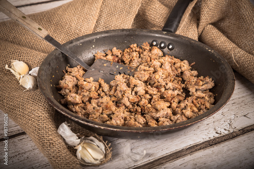 фотография Cooking Ground sausage meat in frying pan with garlic and burlap background