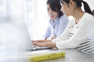 two females, are using a notebook computer in the office