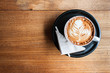 A cup of cappucino and a napkin on a wood background