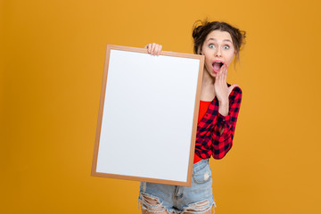 Poster - Amazed happy young woman holding blank board