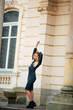 © ostap_davydiak - Young girl posing in a  dress for the camera on a background of brown wooden door column with copy space for your text message or content, confident stylish woman looks to the side
