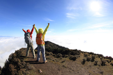 two successful  hikers cheering to sunrise on mountain peak