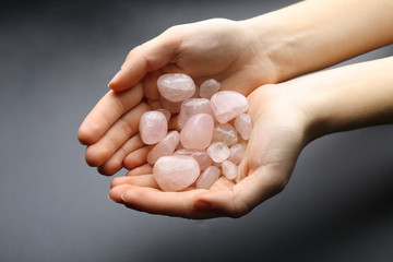 Canvas Print - Woman holding semiprecious stones in her hands on dark grey background