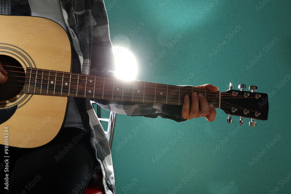 Musician plays guitar on blue background, close up