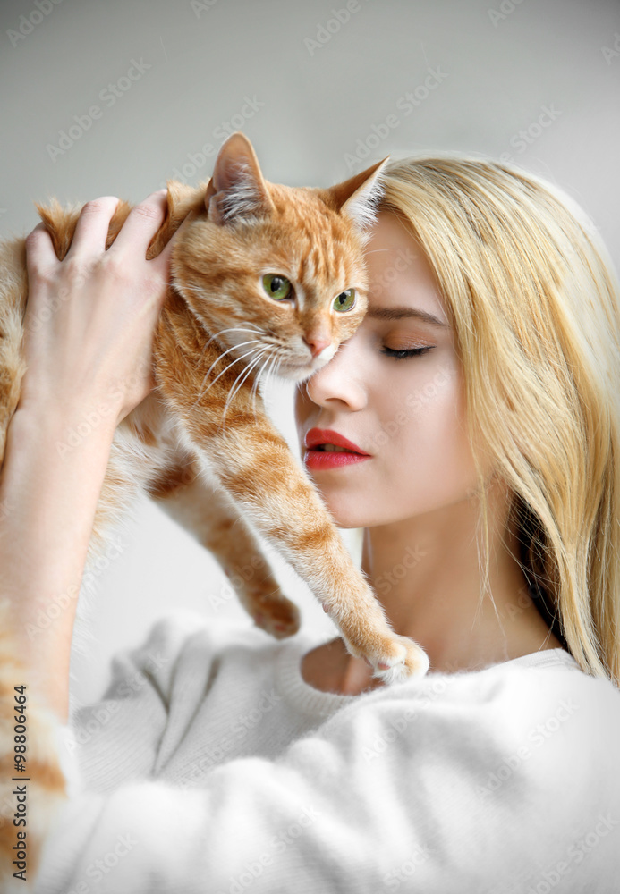 Young woman holds red cat in hands, close up