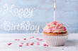 Delicious birthday cupcake on wooden background