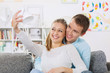 © cherryandbees - Beautiful girl taking a selfie of herself and her boyfriend on the living room couch