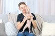 © Africa Studio - Young handsome man holding a cat on couch at home
