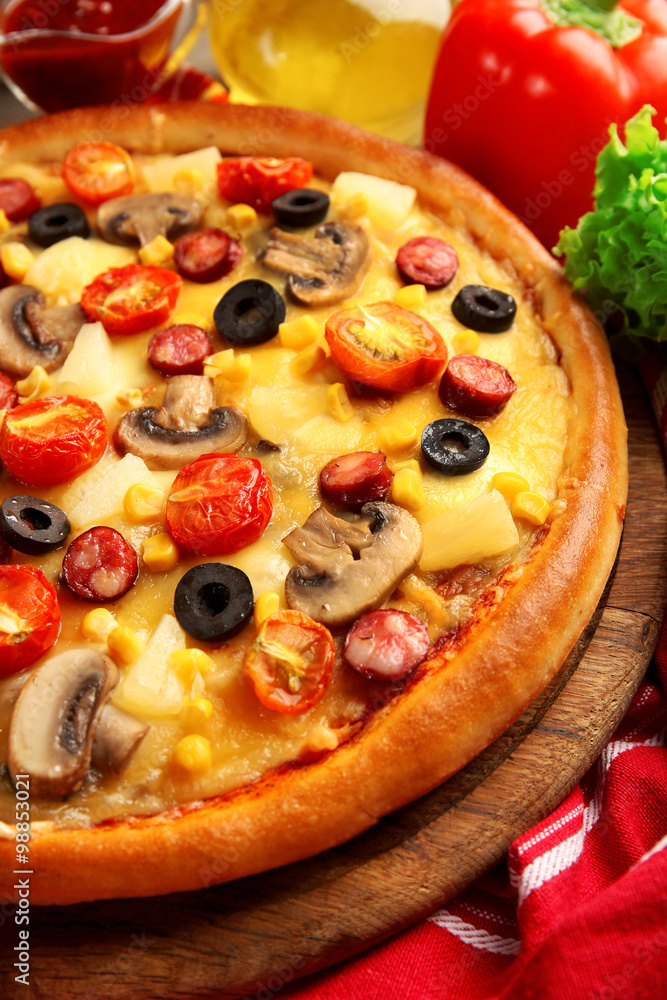 Delicious pizza with vegetables, meat on red napkin, close-up