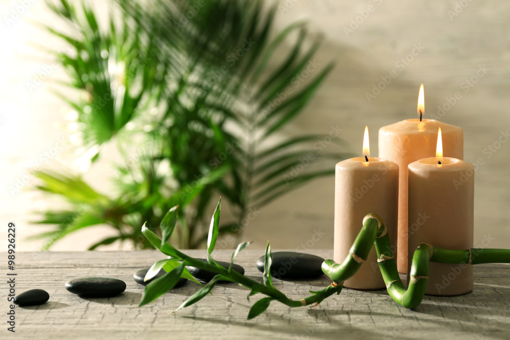 Spa composition of candles, stones and bamboo on light background