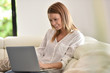 © goodluz - Woman relaxing in sofa and websurfing with laptop