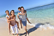 © goodluz - Parents giving piggyback ride to kids on a sandy beach