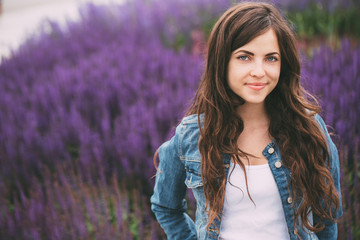 Female teenager in jeans jacket smiling outdoors. Toned.