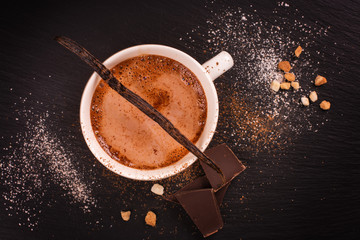 Hot chocolate in white porcelain cup over black stone background