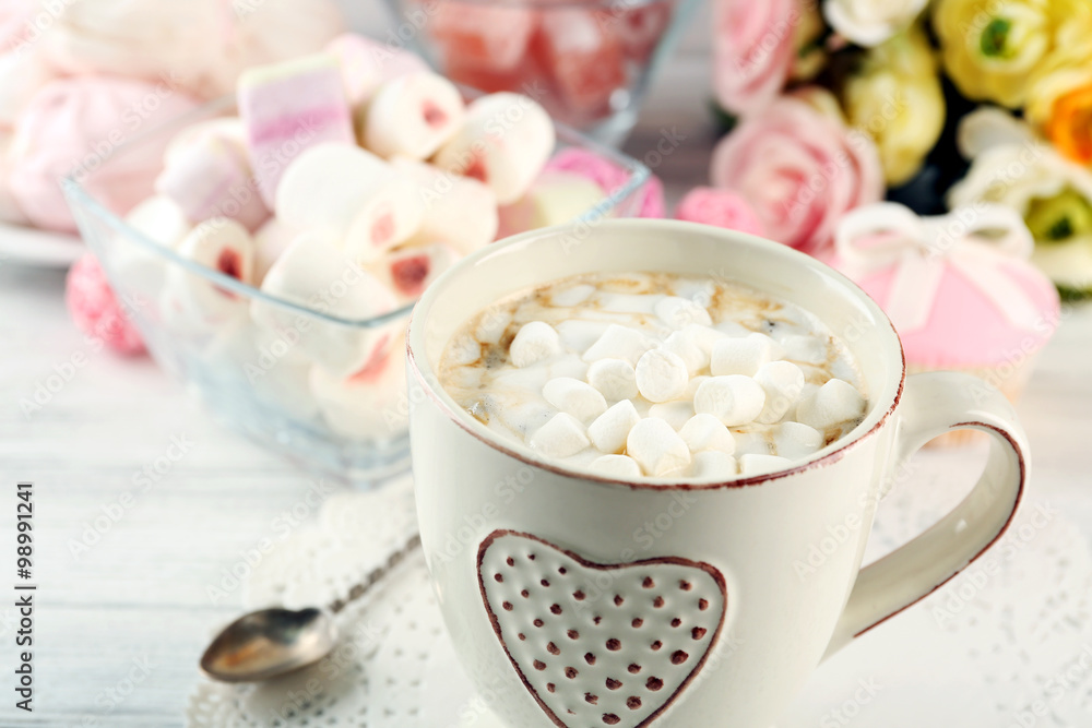 Mug of hot chocolate with marshmallows, on light wooden background