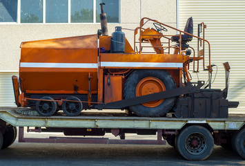 A paver finisher, asphalt finisher or paving machine waiting to be transported on a road being asphalted