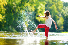 Cute Little Girl Having Fun By A River On Warm Summer Day