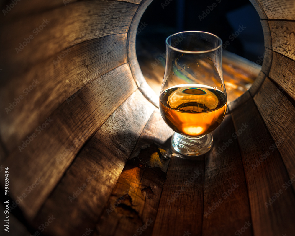 A glass of whiskey in oak barrels - obrazy, fototapety, plakaty 