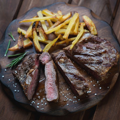 Wall Mural - Sliced medium grilled ribeye steak with french fries, closeup