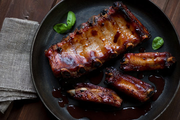 Wall Mural - Baked pork ribs served with sauce in a frying pan, above view