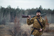 © endrews21 - brutal hunter, bearded man in warm hat with a gun in his hand, a knife a backpack and smoking pipe in the wild forest in the autumn