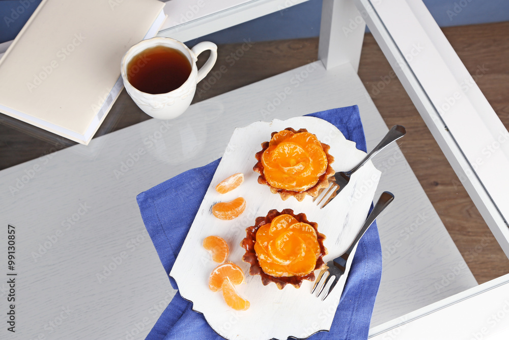 Sweet cakes with tangerines on table, close up