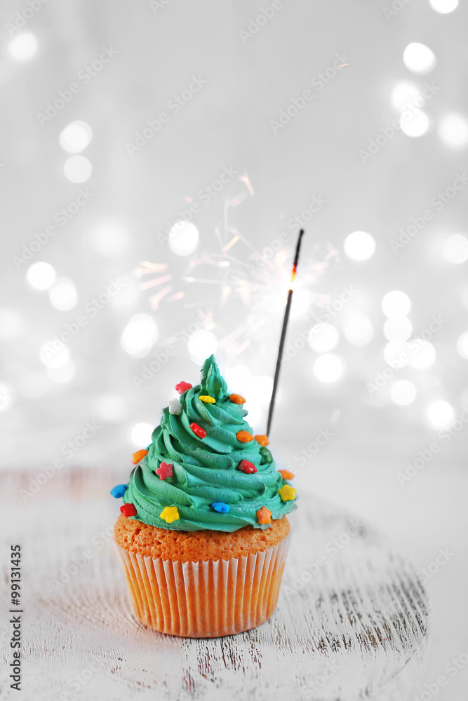 Christmas cupcake with sparkler and lights on background