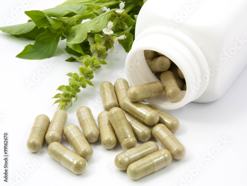 Fotografia herb capsules spilling out of a bottle