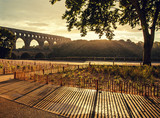 Sun shines through falling raindrops while setting down at Pond du Gard - Roman aqueduct, France.