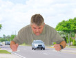Road rage with angry man slamming his fists down on the road around a car as he screams at the car driver