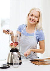 Wall Mural - smiling woman with blender preparing shake at home