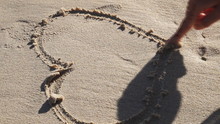 The Woman Draws Heart In The Sand