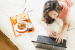 © santypan - Woman watching the laptop computer and having breakfast.