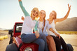 © Monkey Business - Three Female Friends On Road Trip Sit On Car Hood