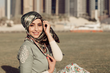 Wall Mural - Smiling girl in hijab covering her eyes with happiness in Dubai Marina