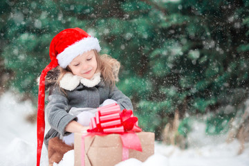 Wall Mural - Little girl with Christmas box gift in winter outdoors on Xmas eve