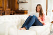 © Minerva Studio - Young woman using a tablet computer while sitting on the sofa