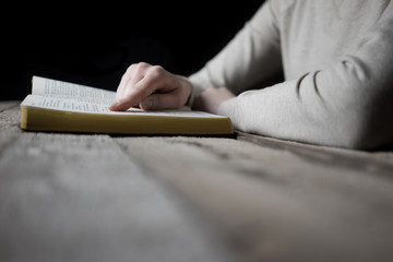 Sticker - woman reading the bible in the darkness over wooden table