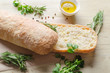 Sliced bread ciabatta watered with extra virgin olive oil with herbs  on wooden background. View from above.