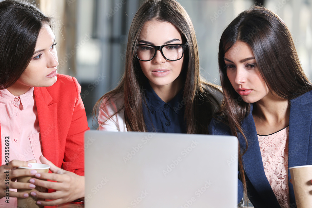 Attractive stylish girls with with laptop speaking in cafe