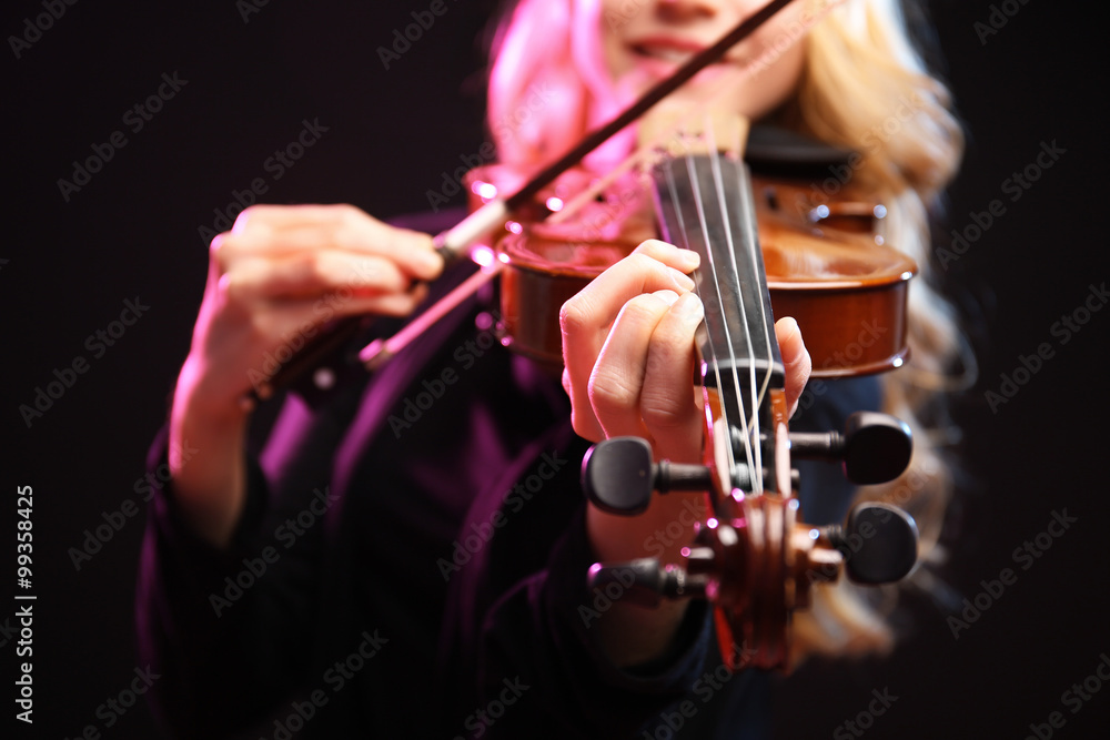 Woman plays violin on black background, close up