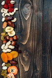 Fototapeta Mapy - Mix of dried fruits and nuts on a dark wood background with copy space. Top view. Symbols of judaic holiday Tu Bishvat