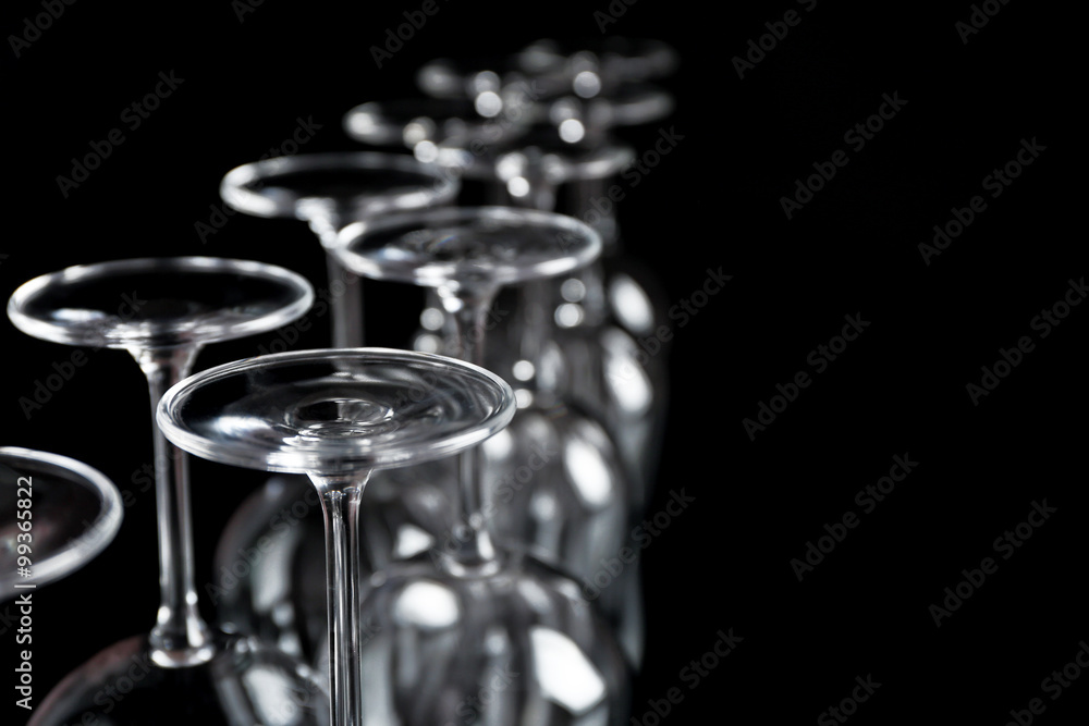 Wine glasses in a row upside down on black background