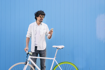 Handsome young man with mobile phone and fixed gear bicycle.