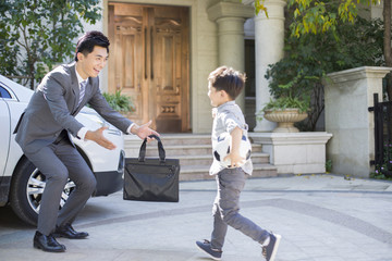 Little boy with football running towards to his father