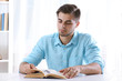 © Africa Studio - Young man reading book at table in room